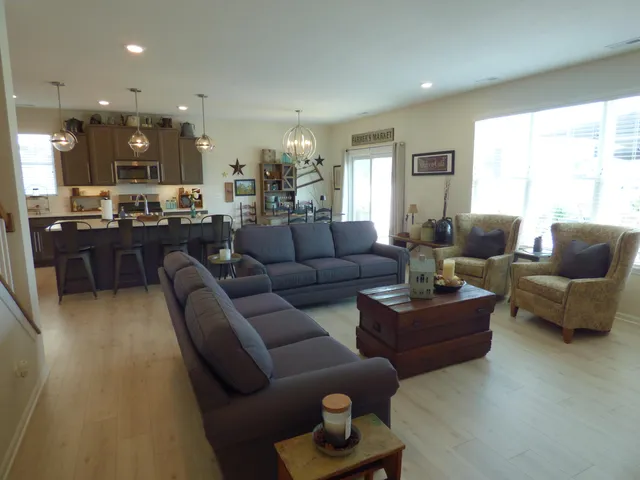 a living room with furniture kitchen view and a large window