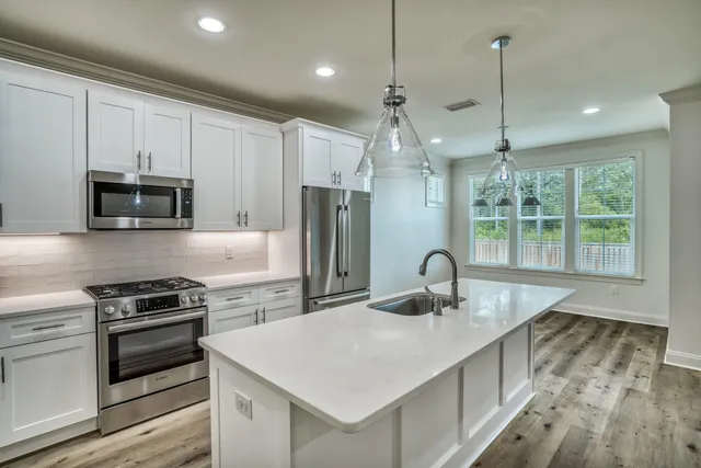 a kitchen with kitchen island granite countertop a sink appliances and cabinets