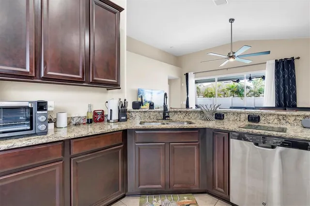 a kitchen with stainless steel appliances granite countertop wooden cabinets a sink and dishwasher with wooden floor