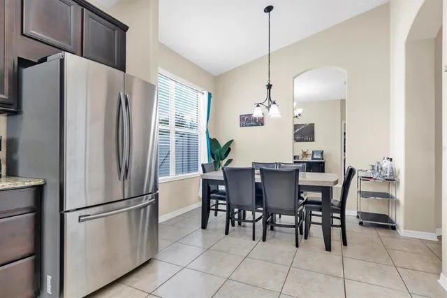 a kitchen with stainless steel appliances granite countertop a refrigerator a sink a stove a dining table and chairs