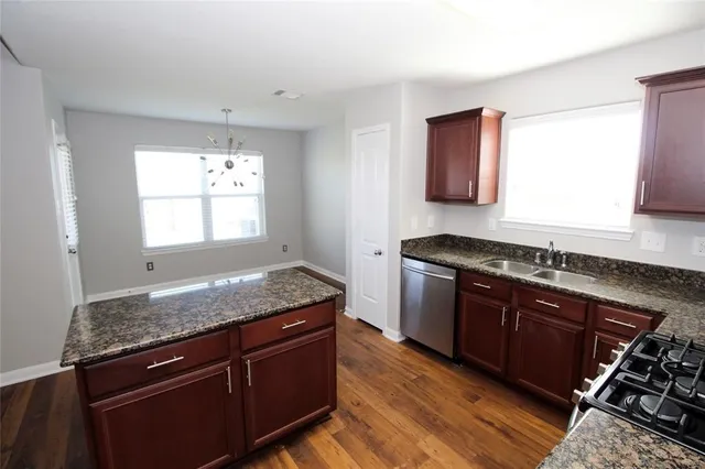 a kitchen with granite countertop stainless steel appliances a stove sink and cabinets