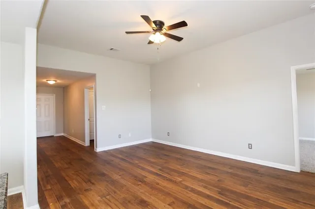 an empty room with wooden floor and a ceiling fan