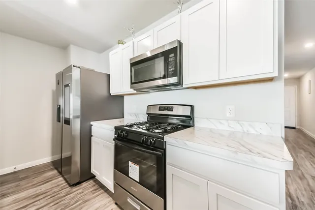 a kitchen with stainless steel appliances white cabinets and a stove top oven