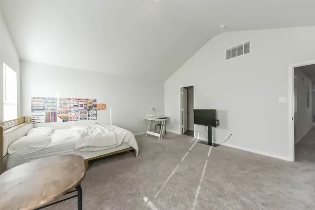 a bedroom with a bed a chair and potted plant on the table