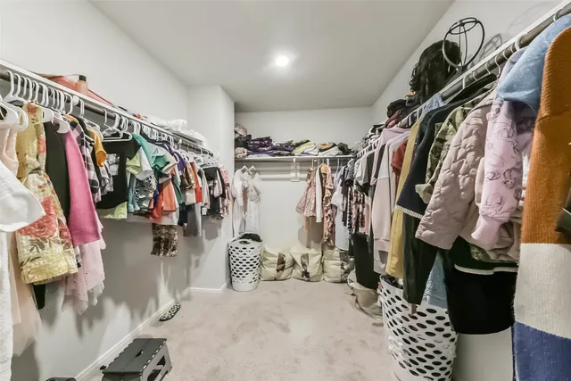 a view of walk in closet with clothes and shoes