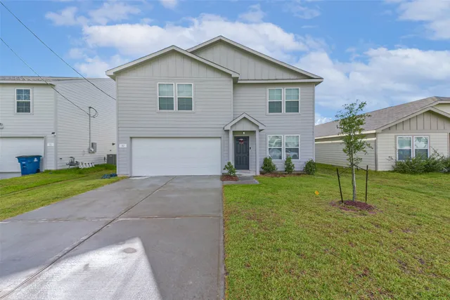 a view of a house with a yard and a large tree