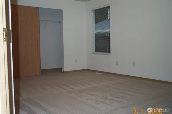 a view of an empty room with wooden floor and closet