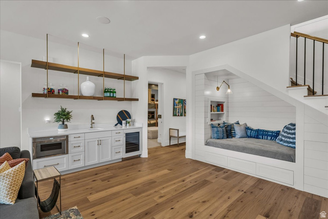 2608 Canyon Ridge Drive St. George, UT 84770 - Photo 60 of 86 Hardwood flooring throughout a versatile space featuring a built-in wet bar with under-counter microwave and beverage cooler, and a custom window seat with integrated shelving and wall sconce lighting