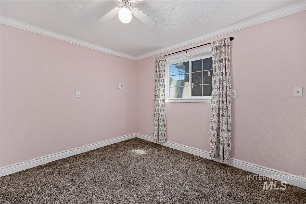 1940 Q Street Heyburn, ID 83336 - Photo 19 of 30 Room with textured pink walls, white crown molding, and white baseboards