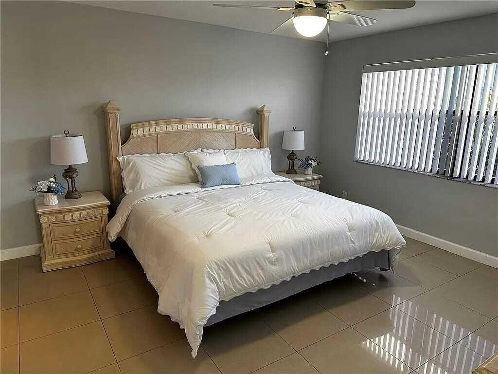 105 South Riverside Drive, Unit 303 Pompano Beach, FL 33062 - Photo 26 of 36 a large bed sitting in a bedroom next to a window