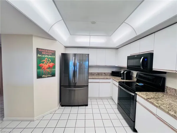 a kitchen with granite countertop a refrigerator and a stove top oven