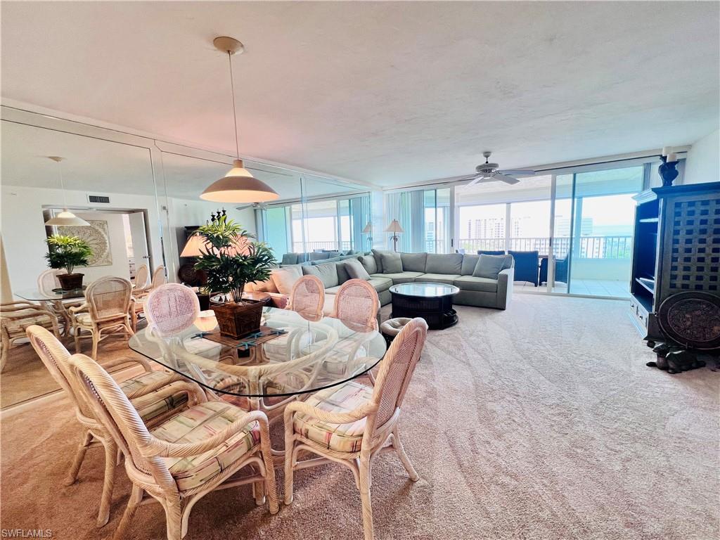 25 Bluebill Avenue, Unit 1002 Naples, FL 34108 - Photo 8 of 34 a view of a dining room and livingroom with furniture a rug a potted plant and a chandelier