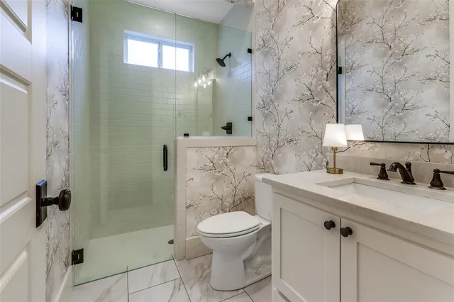 a bathroom with a granite countertop sink a toilet and shower