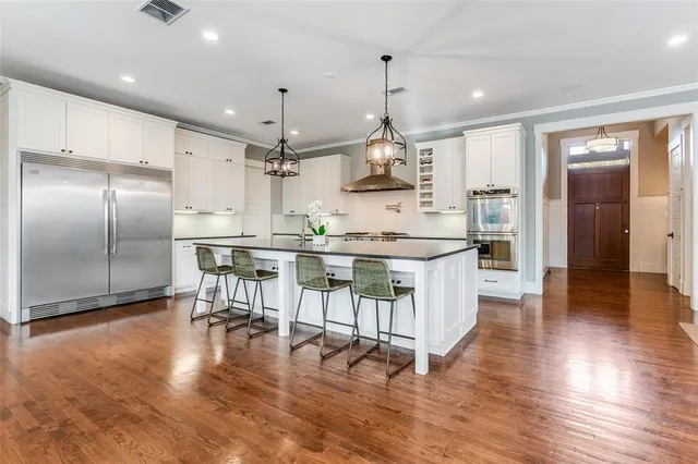 a kitchen with stainless steel appliances kitchen island granite countertop a table chairs and a sink