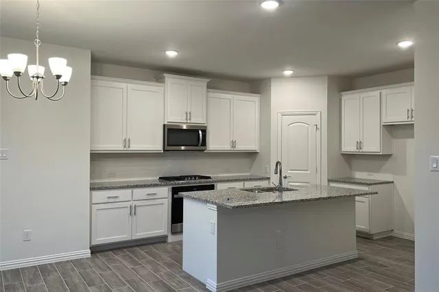 a kitchen with kitchen island granite countertop a sink cabinets and stainless steel appliances