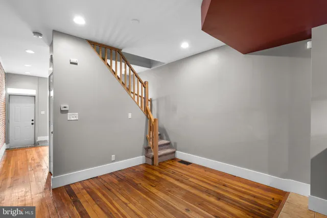 a view of an empty room with wooden floor and stairs