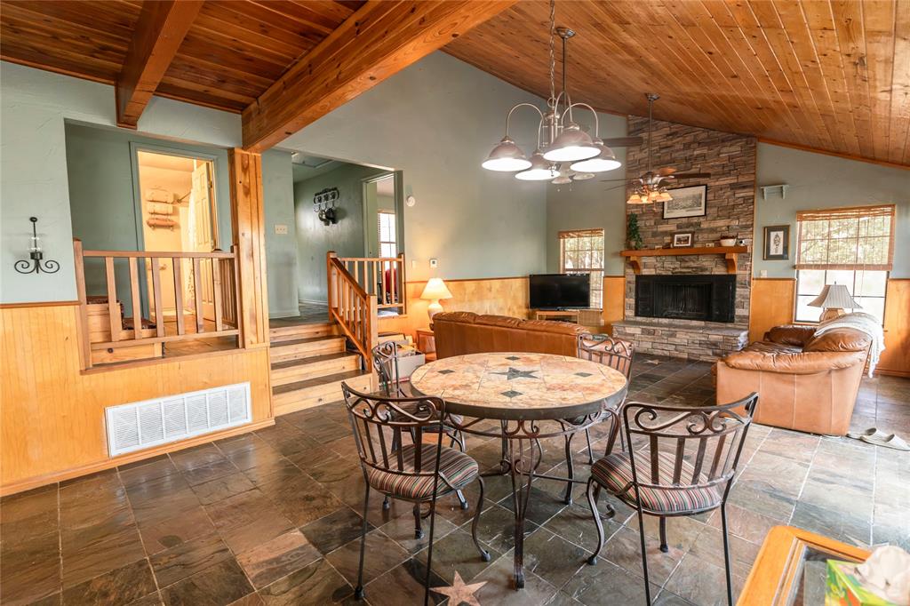 698 Storey Road Nocona, TX 76255 - Photo 23 of 34 Dining space featuring wainscoting, wood walls, wooden ceiling, a fireplace, and a chandelier