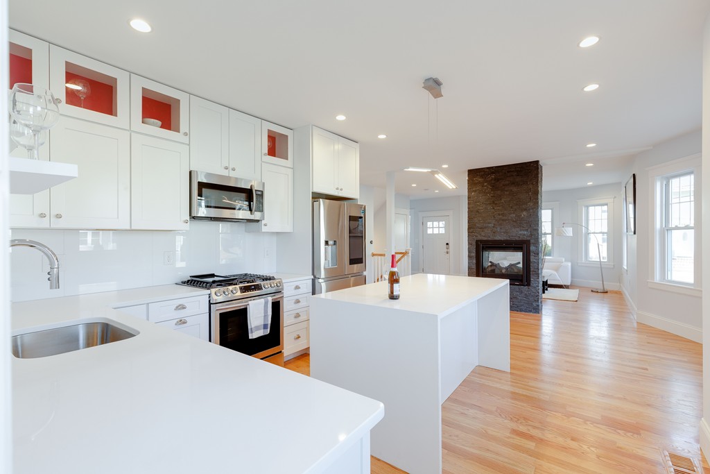 a large white kitchen with cabinets a sink a stove a dining table and chairs