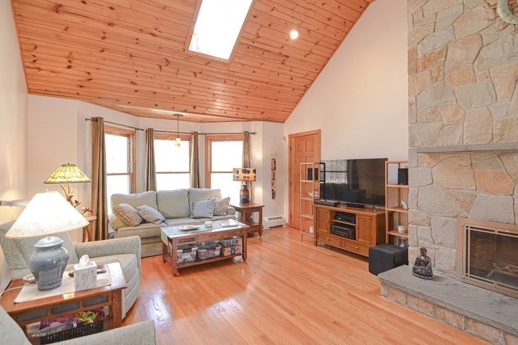 27 Wilson Pond Road Rowley, MA 01969 - Photo 11 of 42 a living room with furniture a fireplace a flat screen tv and a large window