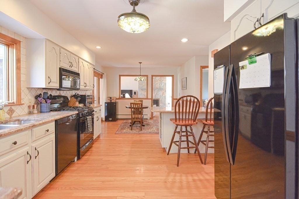 27 Wilson Pond Road Rowley, MA 01969 - Photo 16 of 42 a open kitchen with stainless steel appliances granite countertop a stove top oven a sink dishwasher and white cabinets with wooden floor