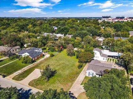 an aerial view of residential houses with outdoor space and trees all around