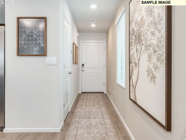 a view of a hallway with wooden floor and a bathroom