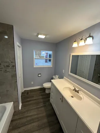 a bathroom with a double vanity sink and mirror with toilet