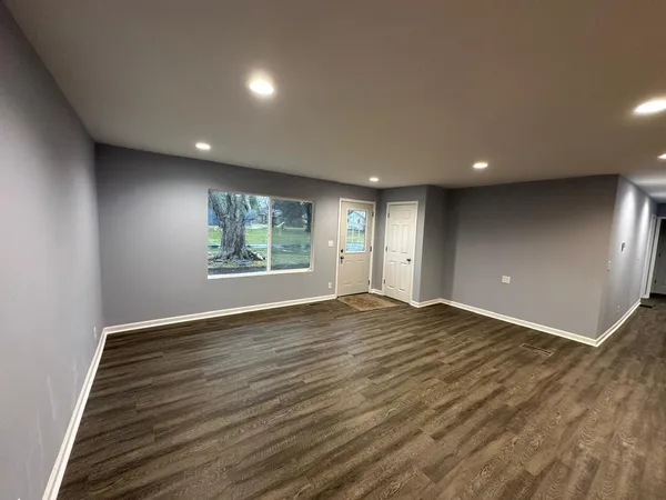 an empty room with wooden floor and windows