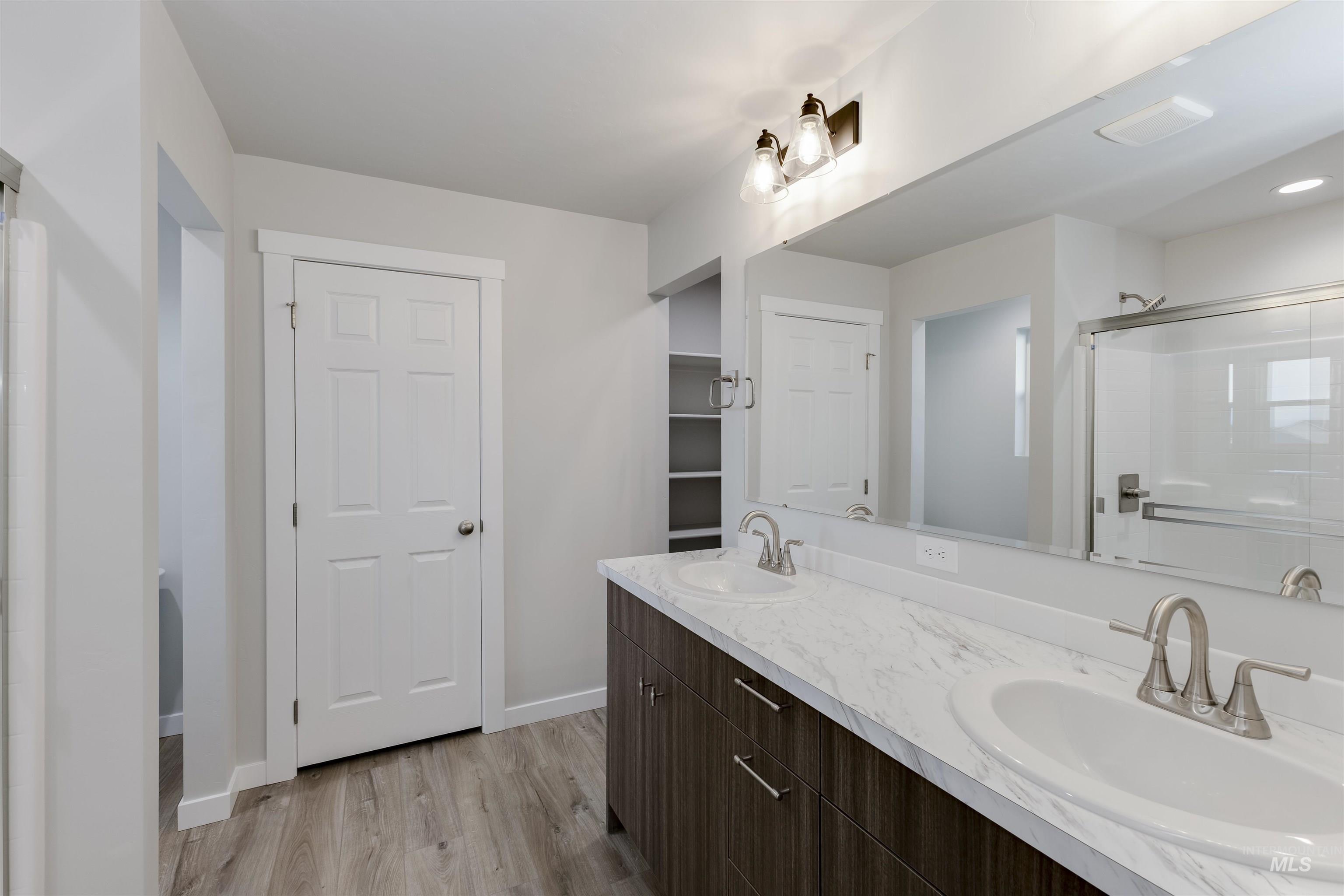 10865 Rutland Street Caldwell, ID 83605 - Photo 17 of 20 Bathroom with a shower stall, double vanity, and light wood-style flooring