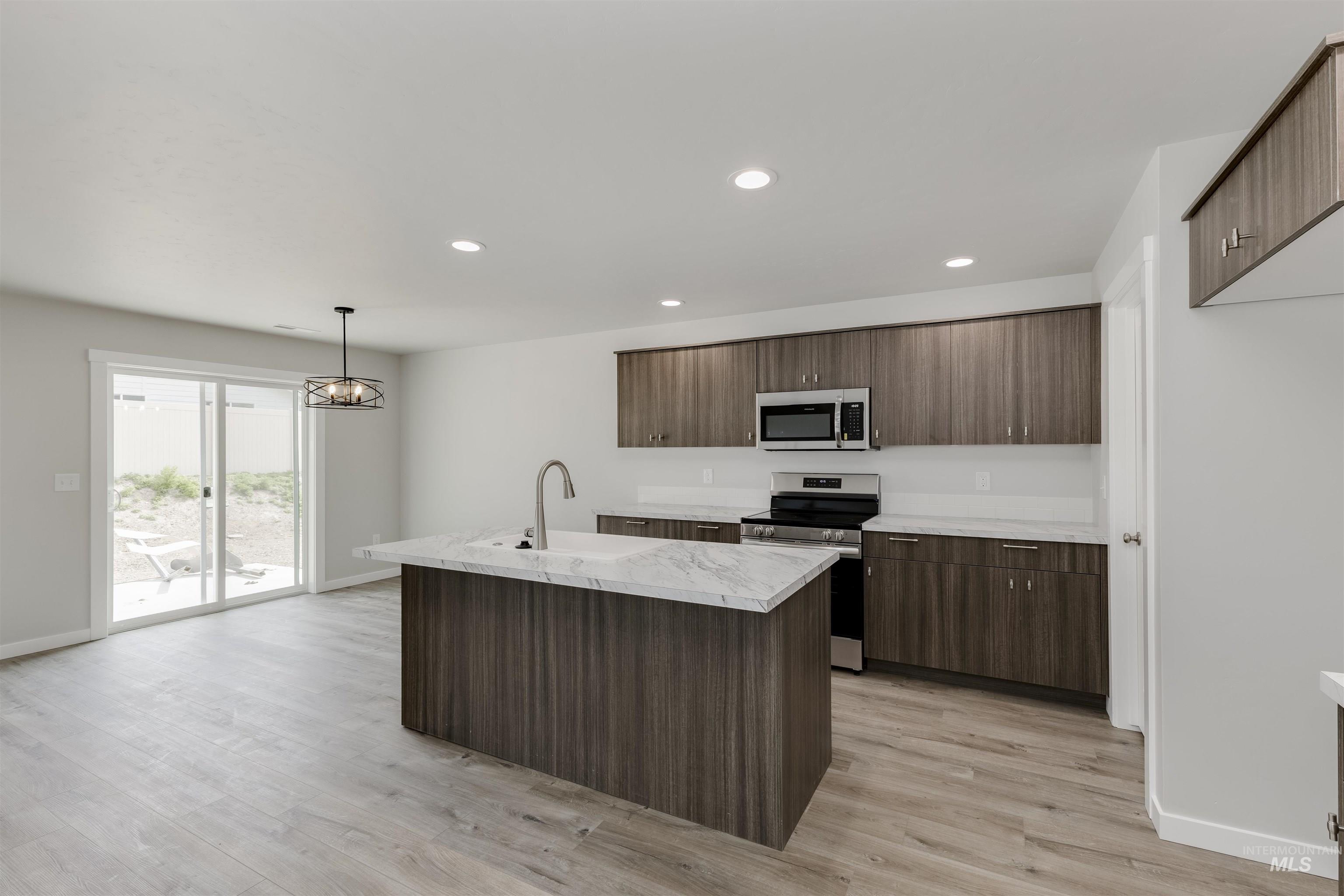 10865 Rutland Street Caldwell, ID 83605 - Photo 3 of 20 Kitchen with stainless steel appliances, hanging light fixtures, a kitchen island with sink, recessed lighting, and light wood-style flooring