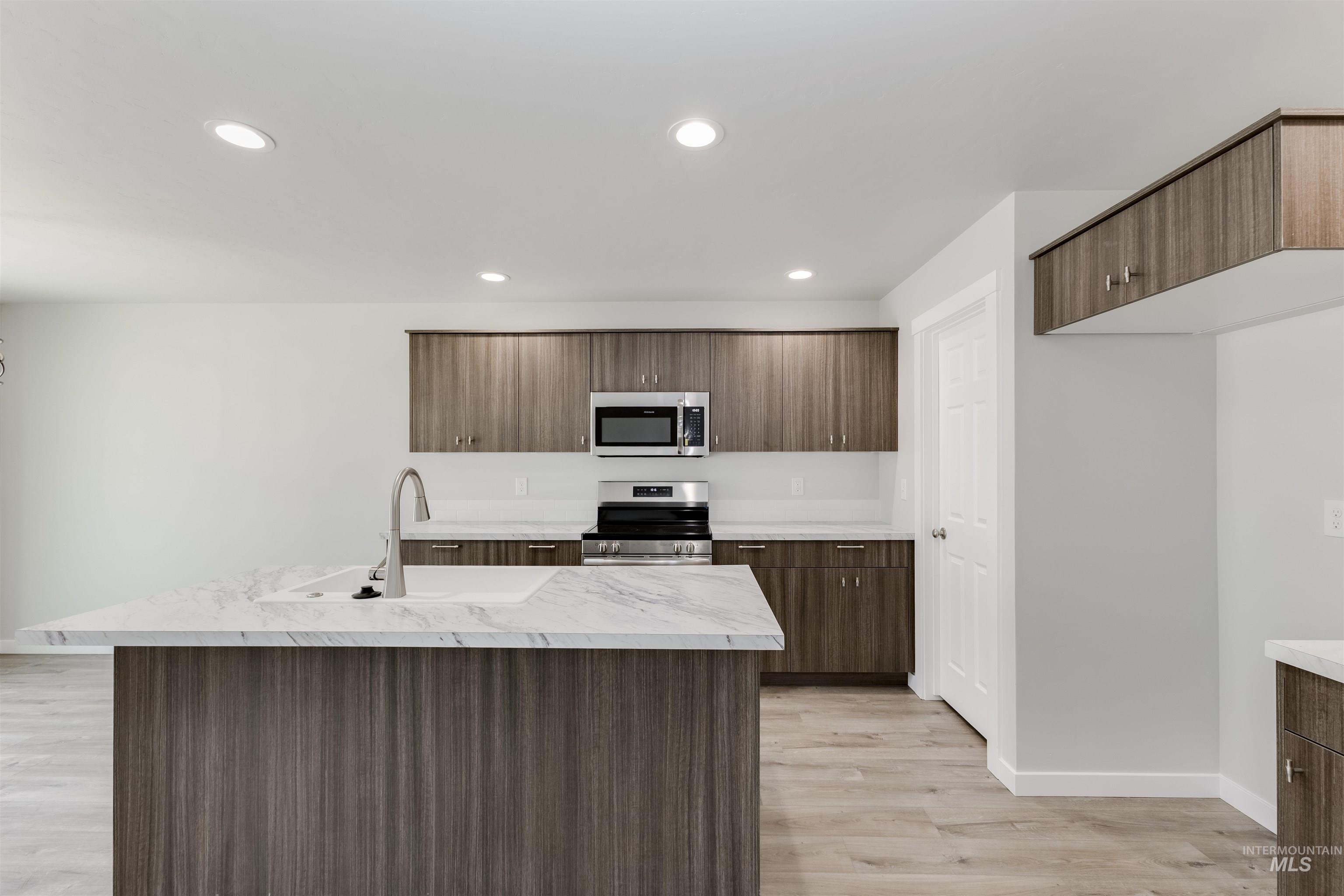 10865 Rutland Street Caldwell, ID 83605 - Photo 4 of 20 Kitchen featuring appliances with stainless steel finishes, light wood-style flooring, recessed lighting, an island with sink, and modern cabinets