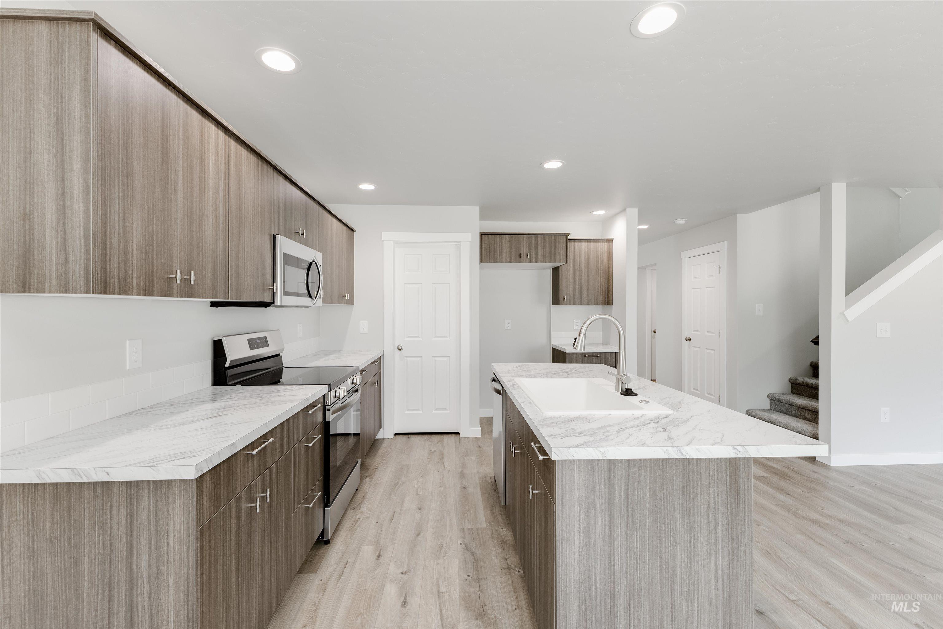 10865 Rutland Street Caldwell, ID 83605 - Photo 6 of 20 Kitchen with stainless steel appliances, modern cabinets, light wood finished floors, a kitchen island with sink, and recessed lighting