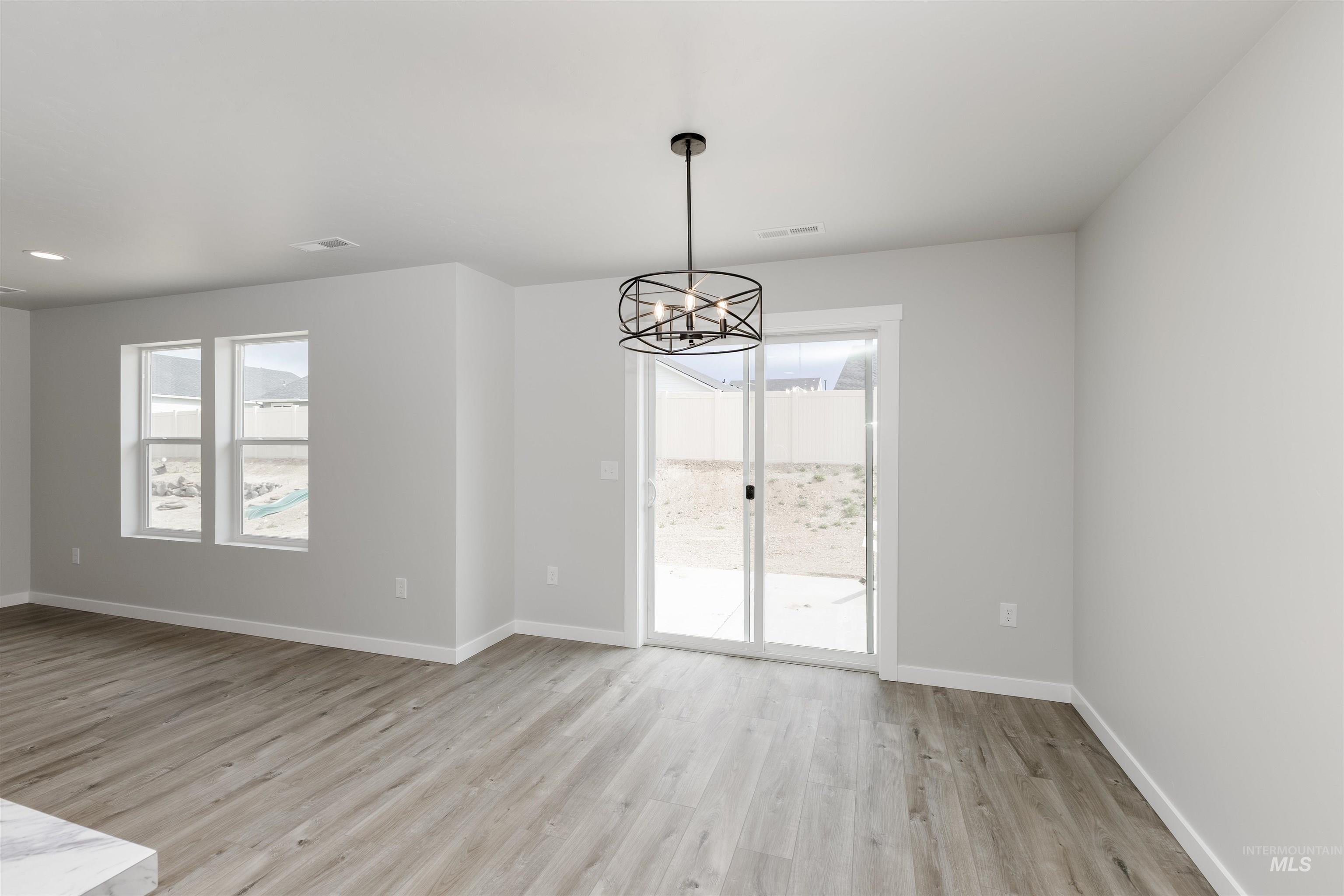 10865 Rutland Street Caldwell, ID 83605 - Photo 7 of 20 Empty room with light wood-type flooring, plenty of natural light, and a chandelier