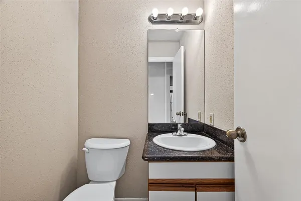 a bathroom with a granite countertop sink and a mirror with toilet