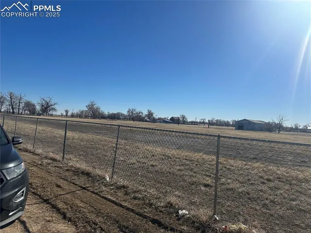 a view of a dry yard with wooden fence