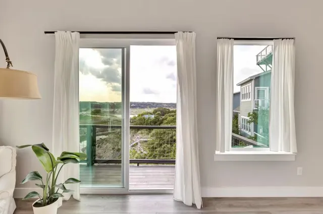 a view of a room that has a large window and wooden floor