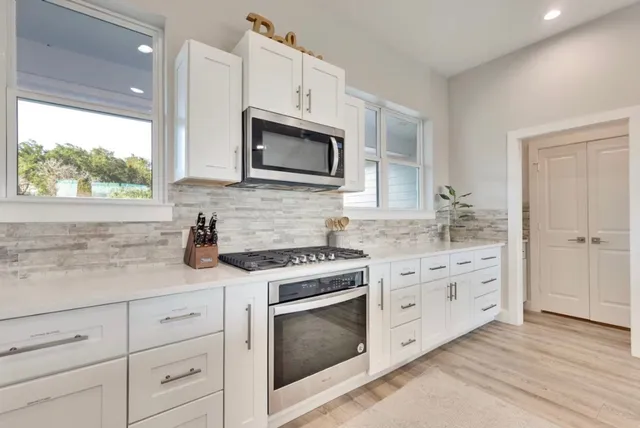 a kitchen with granite countertop white cabinets appliances and a sink