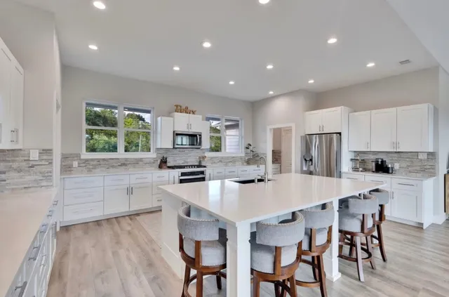 a large kitchen with stainless steel appliances a table and chairs in it
