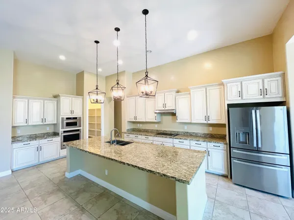 a large kitchen with stainless steel appliances kitchen island granite countertop a refrigerator and a sink
