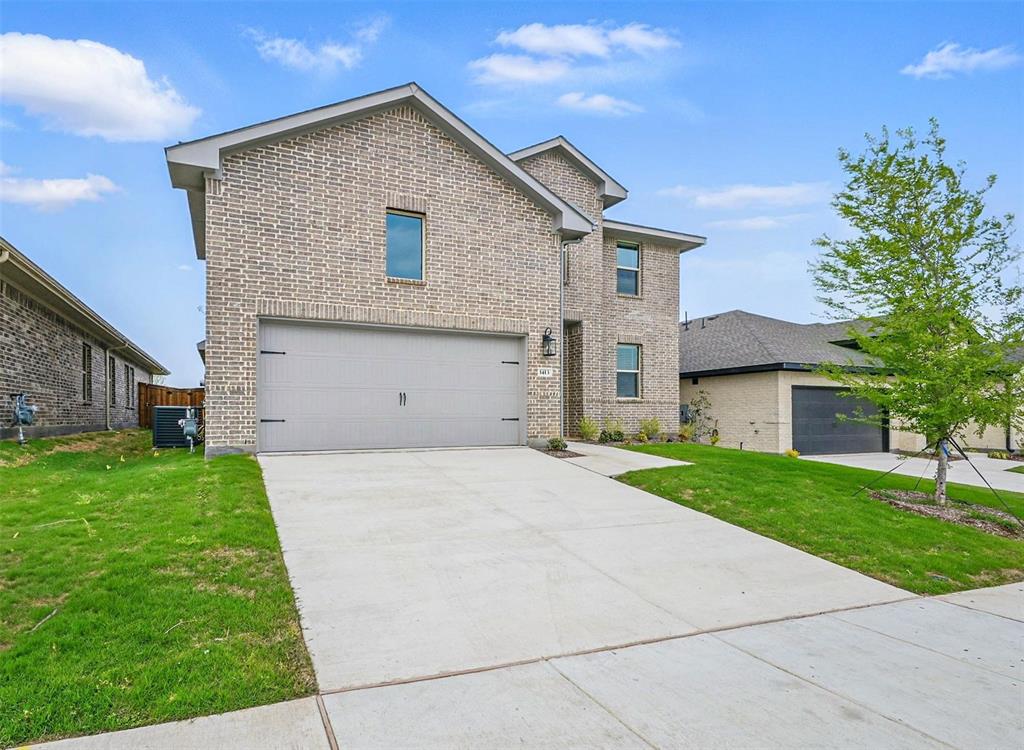 1413 Richardson Street Howe, TX 75459 - Photo 2 of 30 Brick facade residence featuring a two-car garage with decorative hardware, a concrete driveway, and manicured green lawns
