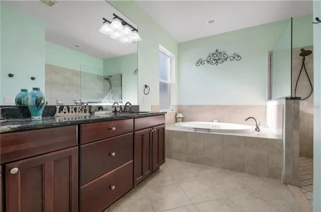 a bathroom with a granite countertop bathtub sink vanity and mirror