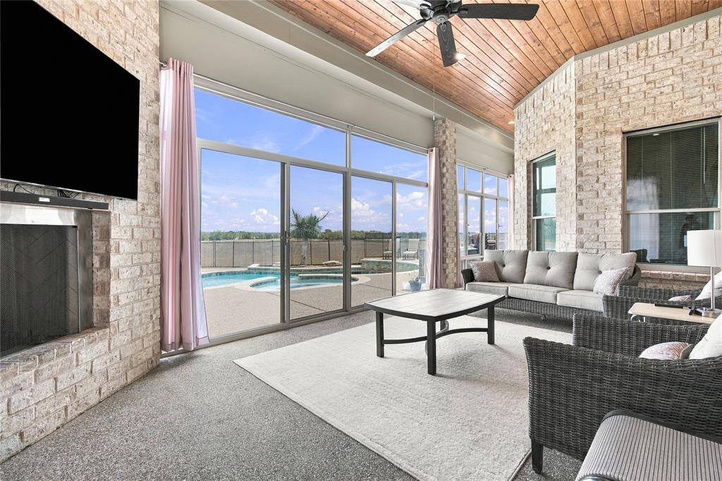 1180 Wiggins Road Maypearl, TX 76064 - Photo 32 of 40 Relax under the vaulted, wood-paneled covered patio, complete with a stone fireplace, ceiling fan, and sliding glass doors that open straight into the living room.