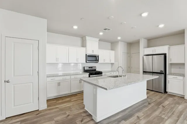 a kitchen with stainless steel appliances granite countertop a stove top oven a sink and a refrigerator