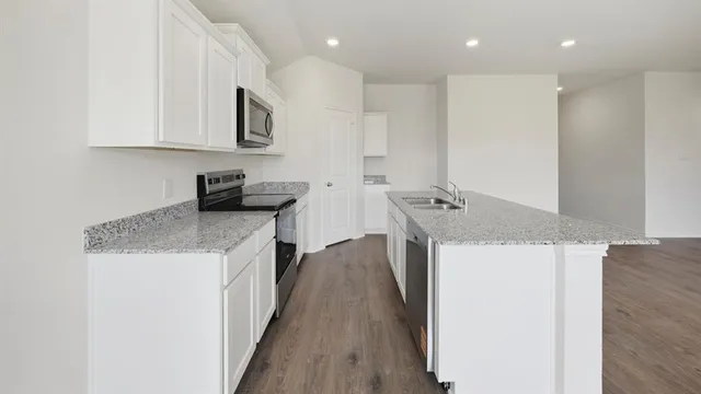 a kitchen with stainless steel appliances granite countertop a sink a stove top oven a counter space and cabinets