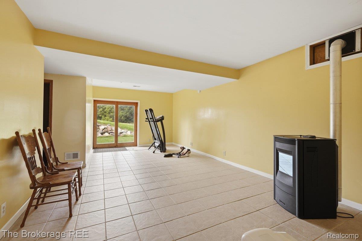 2422 South Henderson Road Davison, MI 48423 - Photo 34 of 53 Spacious room featuring light-toned tile flooring, a built-in black stove, and a wood-framed glass sliding door