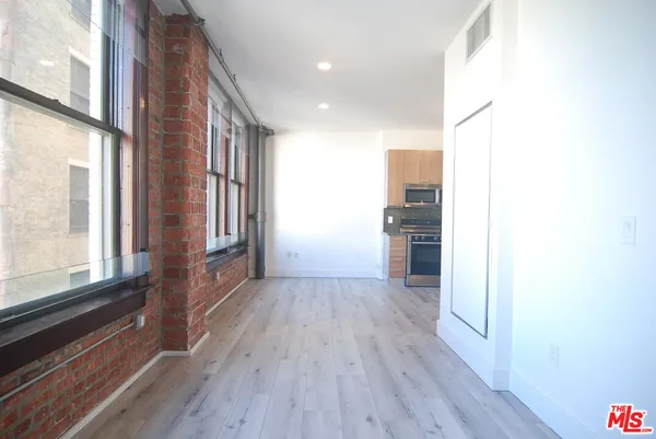 a view of a hallway with wooden floor and a living room