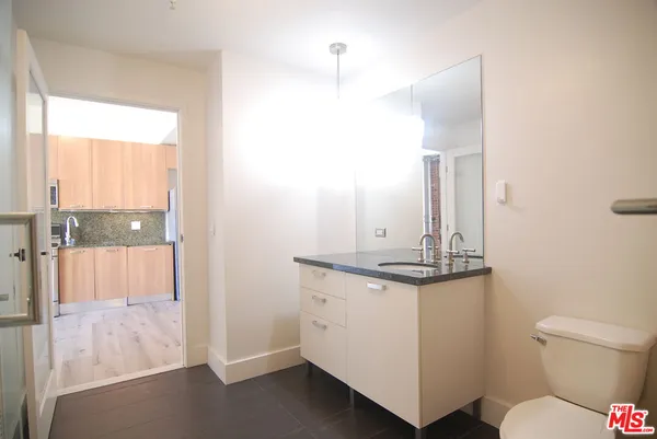 a bathroom with a granite countertop sink a toilet a mirror and shower