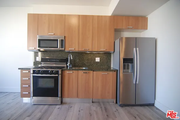 a kitchen with a refrigerator stove and wooden cabinets