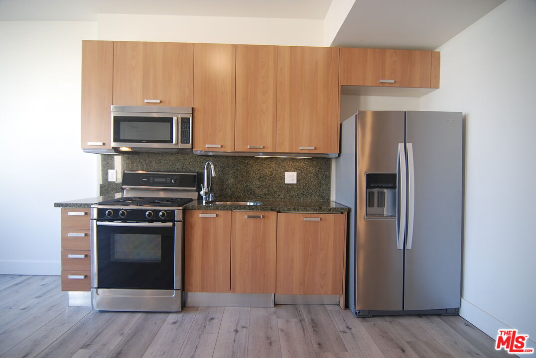 460 South Spring Street, Unit 608 Los Angeles, CA 90013 - Photo 5 of 31 a kitchen with a refrigerator stove and wooden cabinets