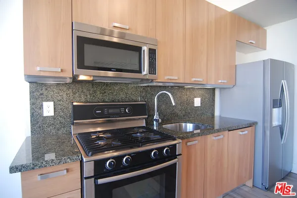 a kitchen with granite countertop a stove and a microwave with cabinets